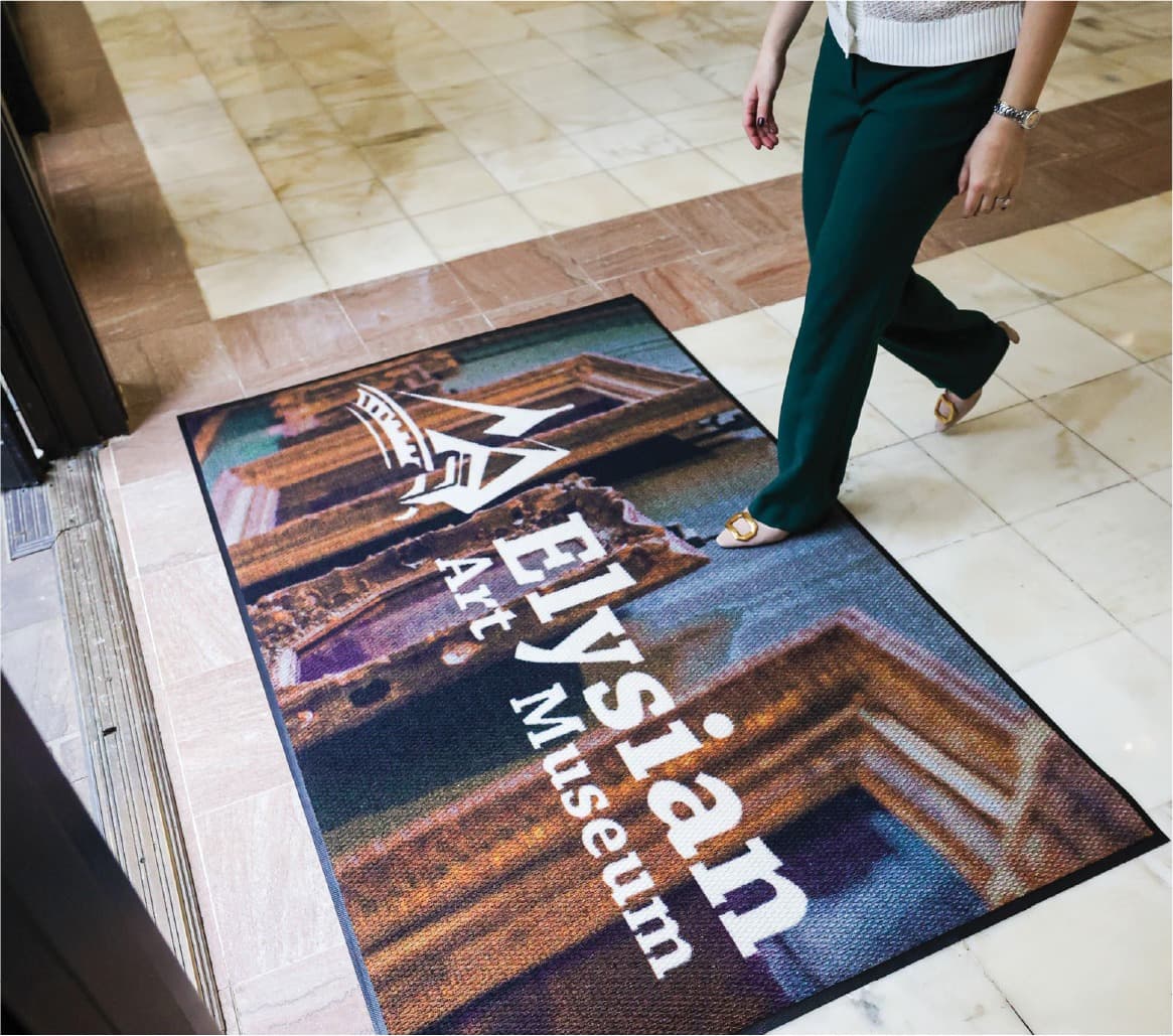 Custom-branded Elysian Art Museum entrance mat with a visitor walking in
