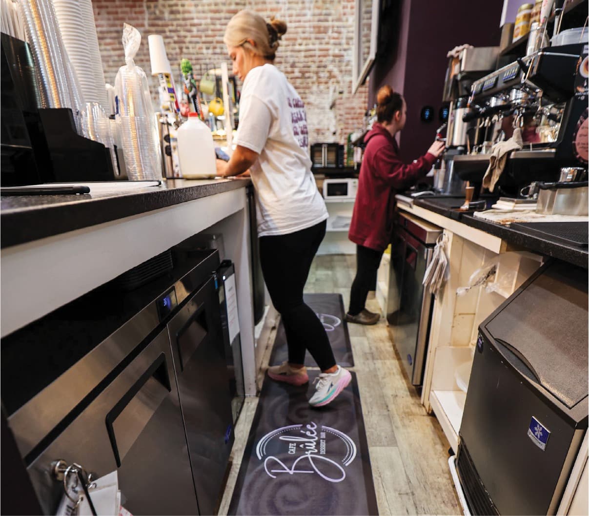 Staff working behind a coffee bar on a branded anti-fatigue mat